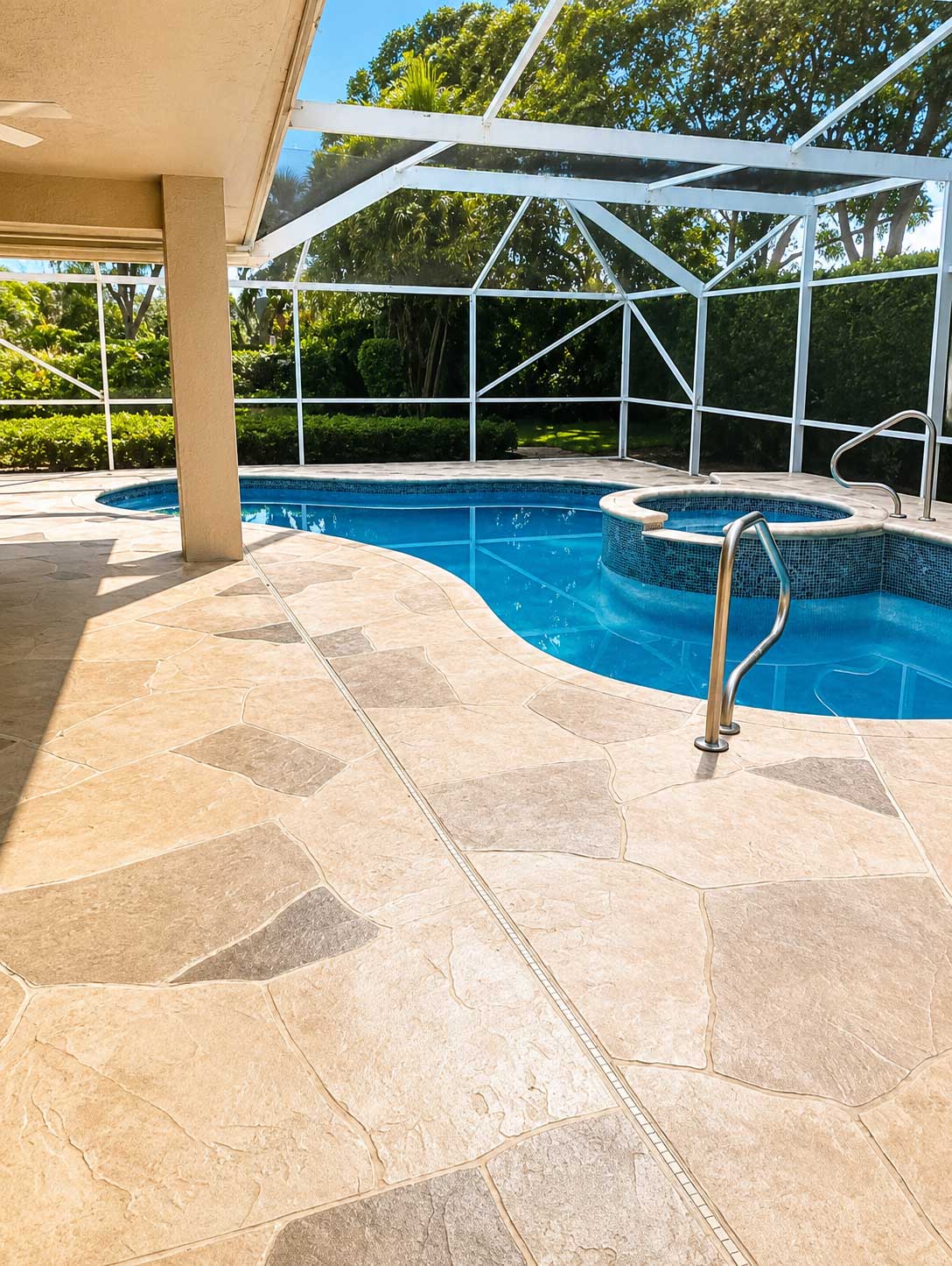 Tan stamped concrete pool deck with a flagstone pattern around a screened pool and spa in Palm Beach and Broward County
