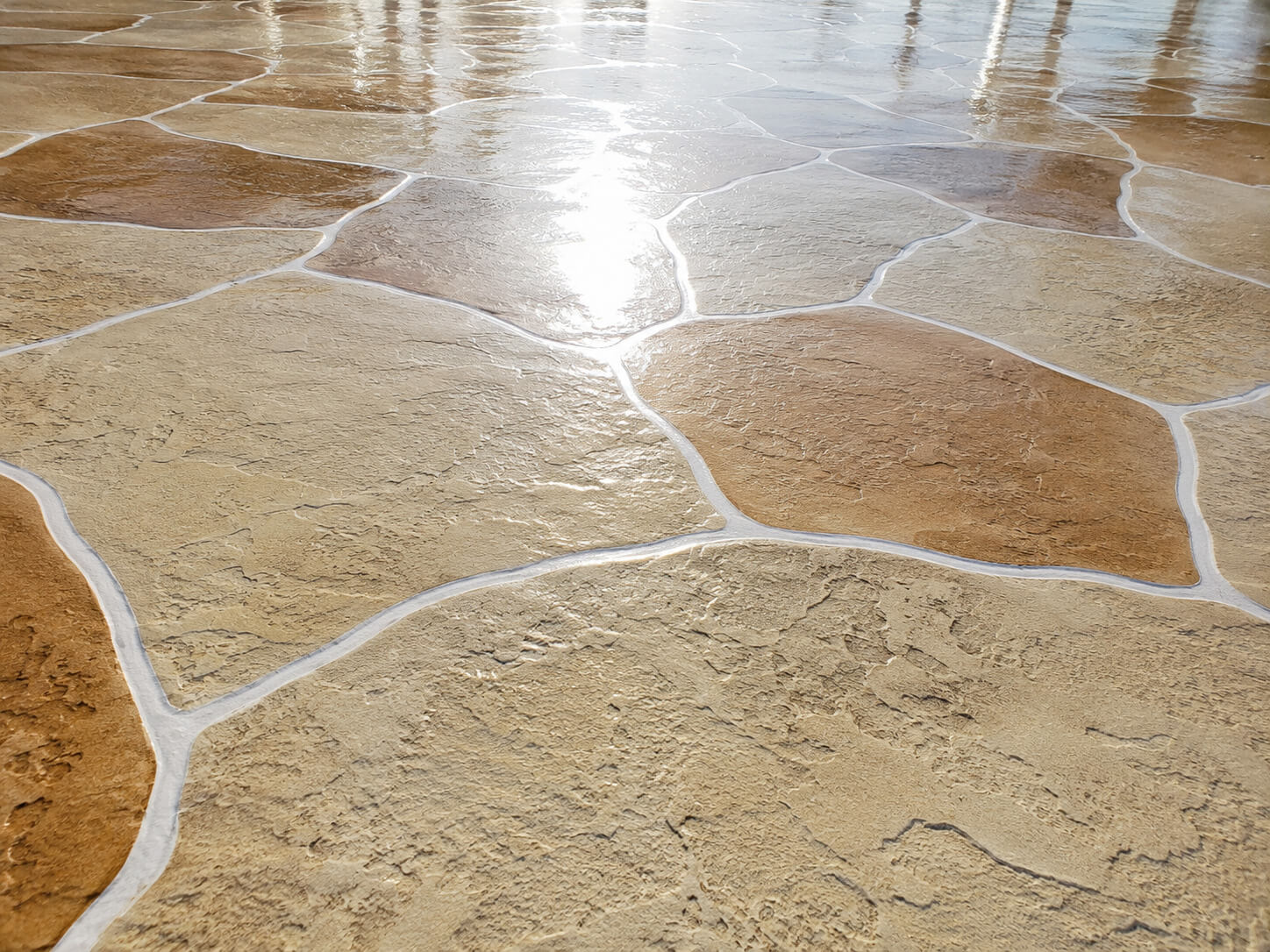 Tan colored stamped concrete patio and walkway overlay with a sealed flagstone finish
