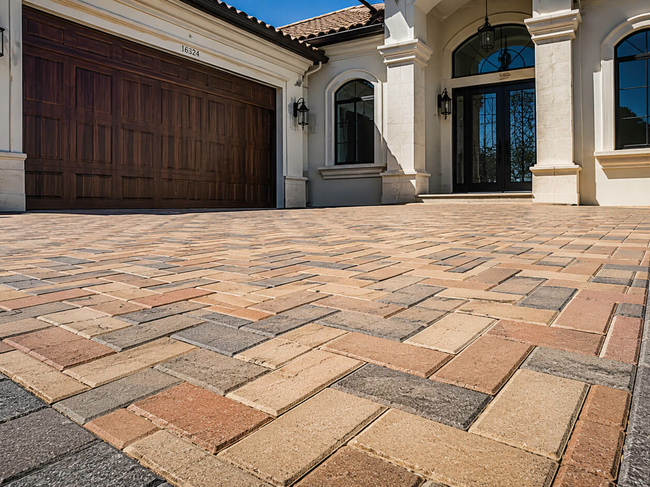 Paver driveway in a blended tan and terracotta herringbone pattern with a charcoal border on a Greenacres property