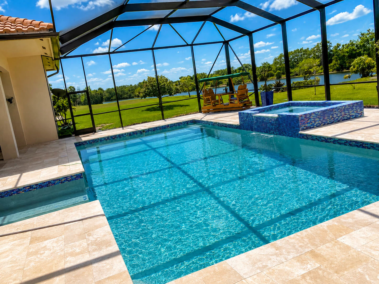 Renovated pool and raised spa with mosaic tile under a screen enclosure on a Palm Beach Gardens pool deck