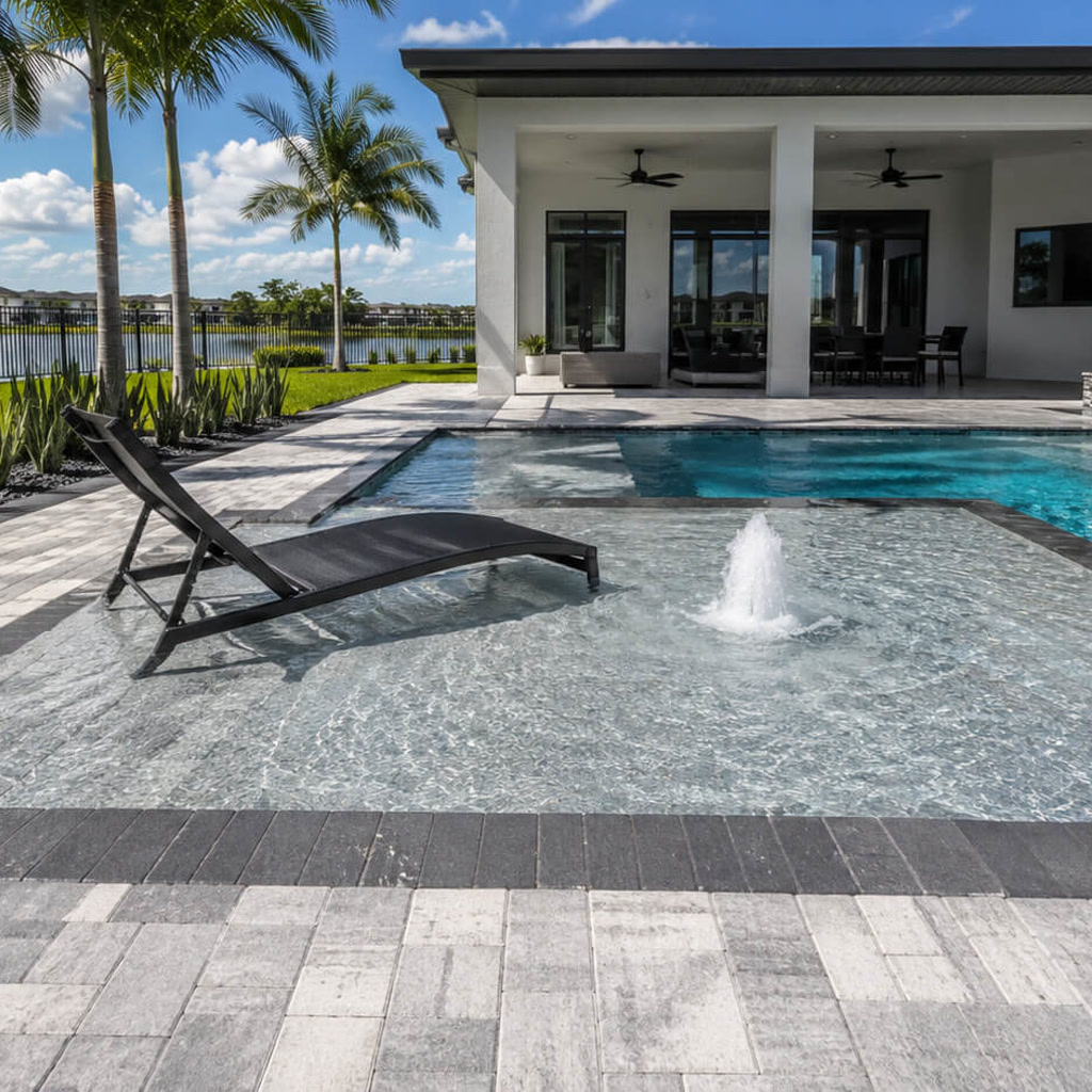 Sun shelf with a bubbler and in water lounger connecting the pool to a covered lanai in a Boynton Beach backyard