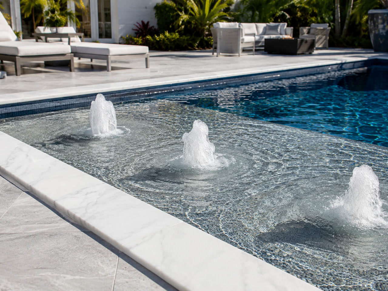 Three bubblers running across a mosaic tiled sun shelf edged in white marble coping at a Jupiter Island estate