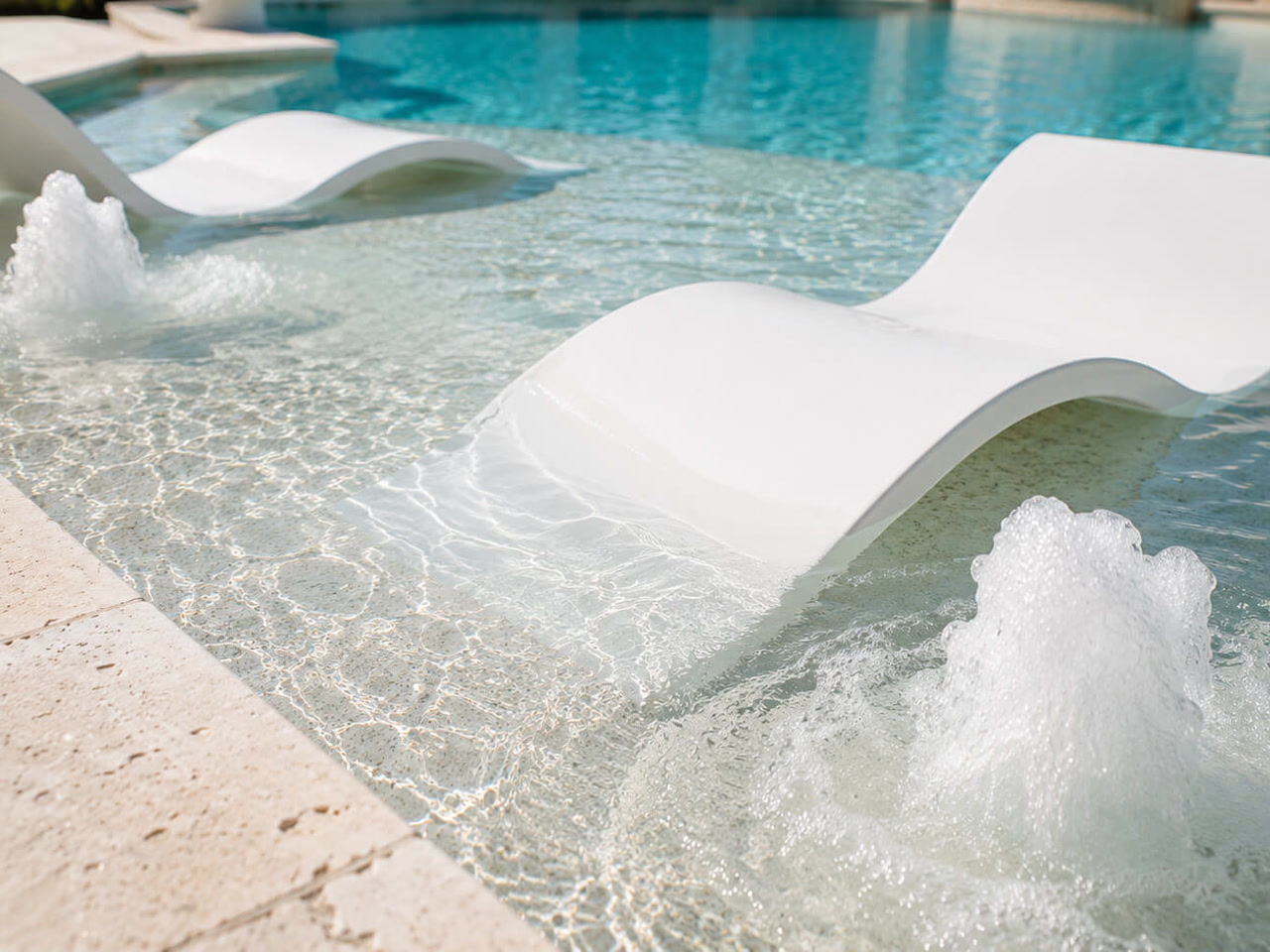 White in water loungers on a shallow sun shelf with bubblers churning on either side at a Parkland pool