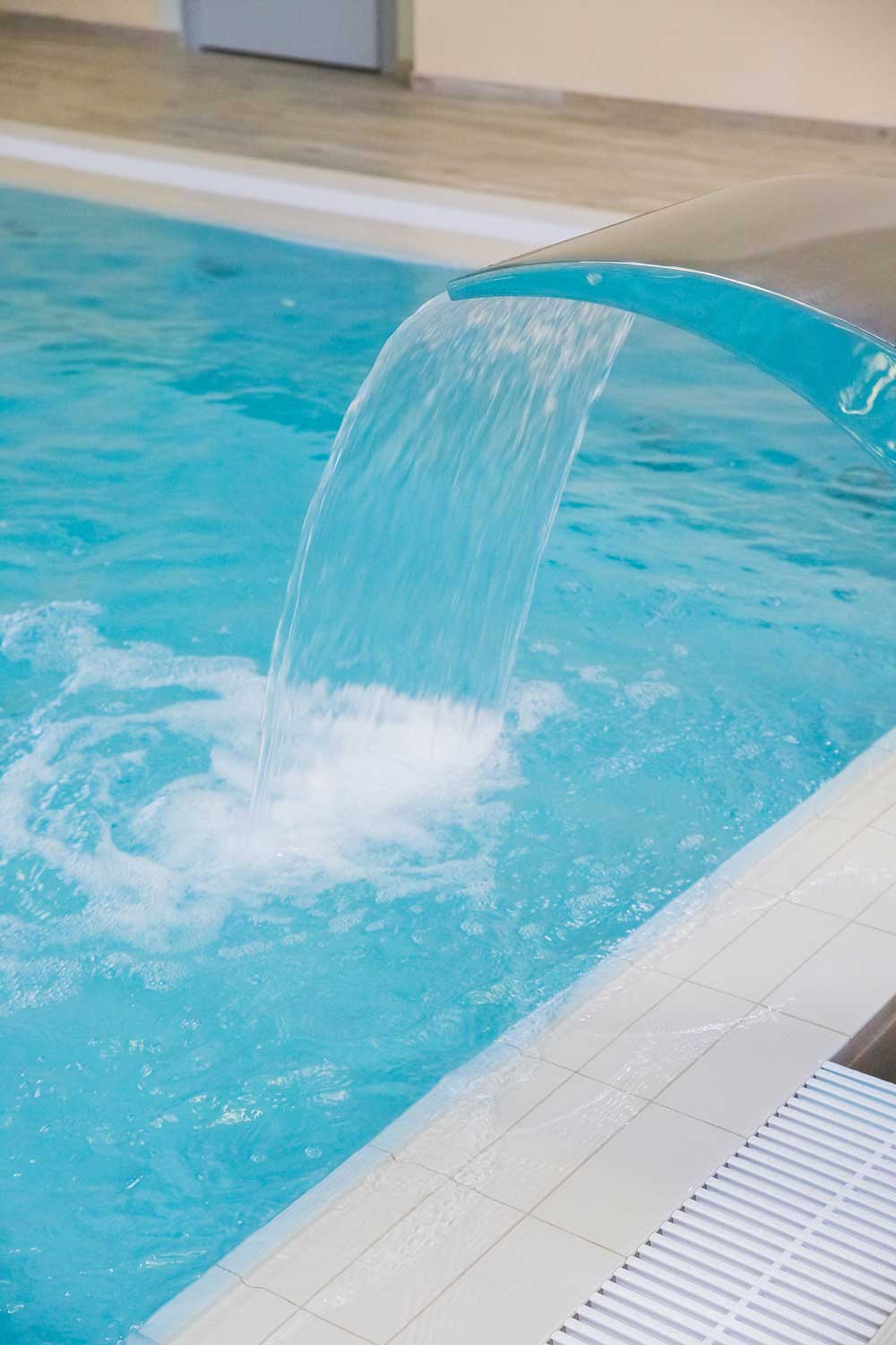 Curved stainless steel waterfall pouring into a swimming pool in Wellington
