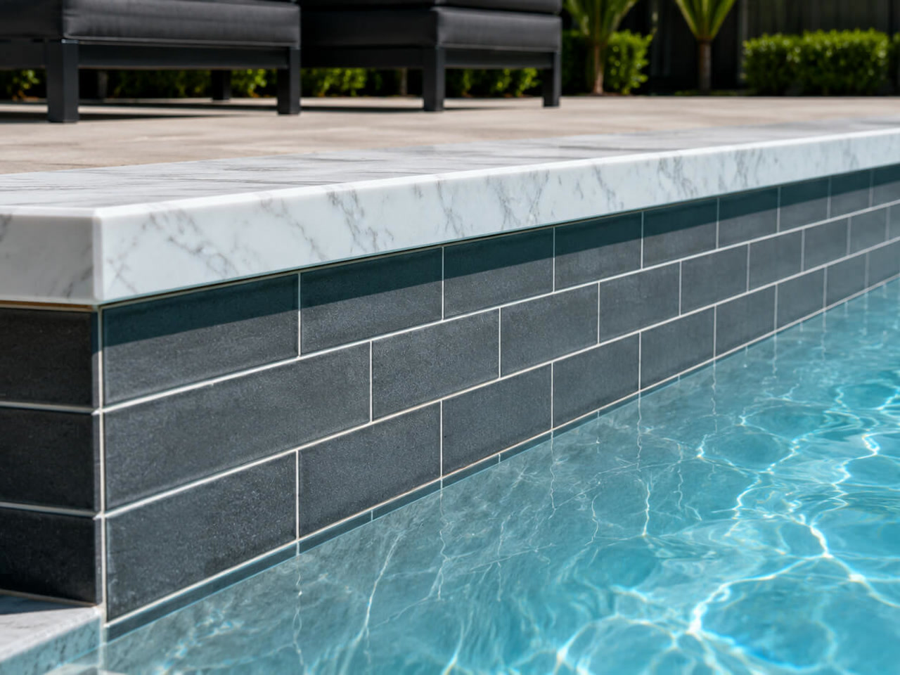 White marble coping cap over charcoal subway tile along the wall of a Delray Beach pool
