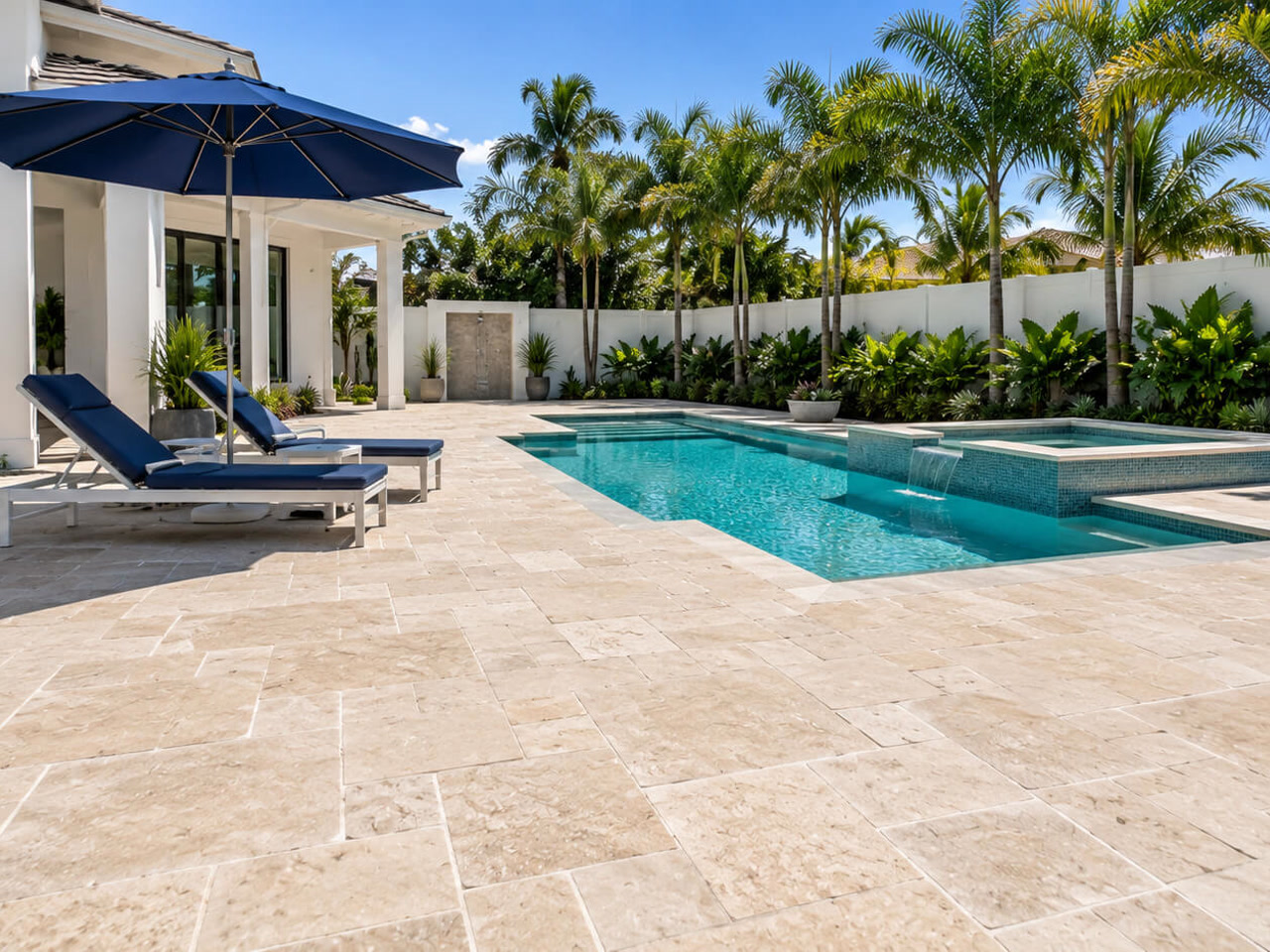Ivory travertine paver pool deck in a French pattern beside a pool with a raised spa and sheer descent